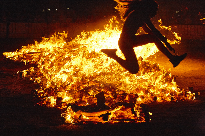 Summer solstice celebration in Spain. Woman jump. Fire flames. Horizontal