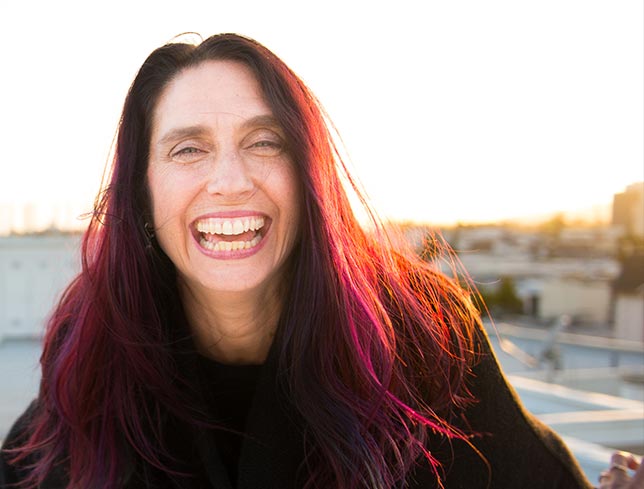 HeatherAsh laughing into the camera, her purple/red hair gently framing her face with joyful abandon.