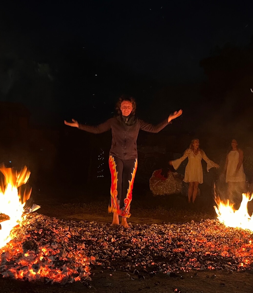 woman walking across hot coals with arms outstretched