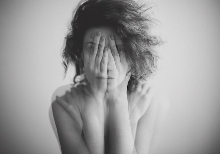 Double exposure black and white portrait of a woman covering her face and eyes with her hands
